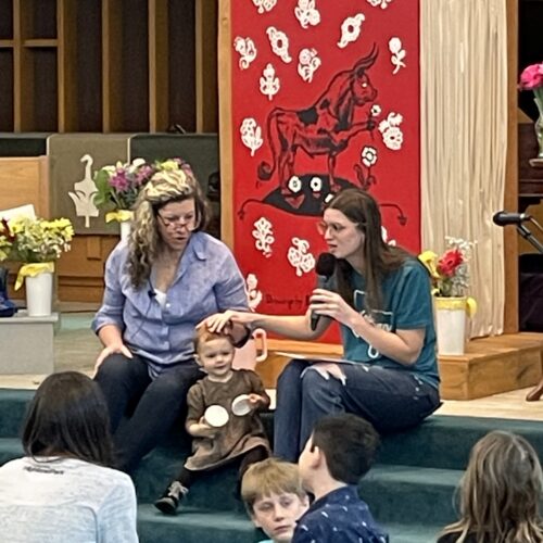 Masyn and Cheryl sit on altar steps talking to children
