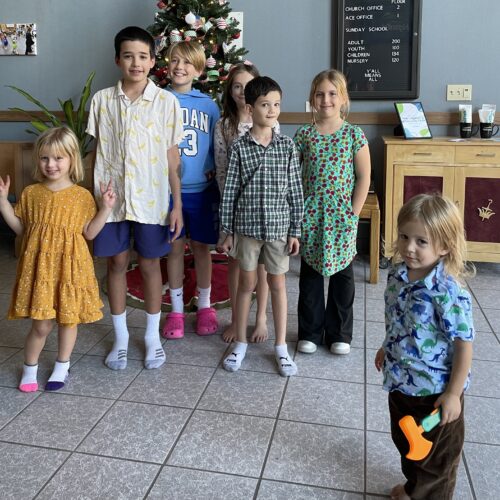 children standing in front of the christmas tree they decorated in the atrium