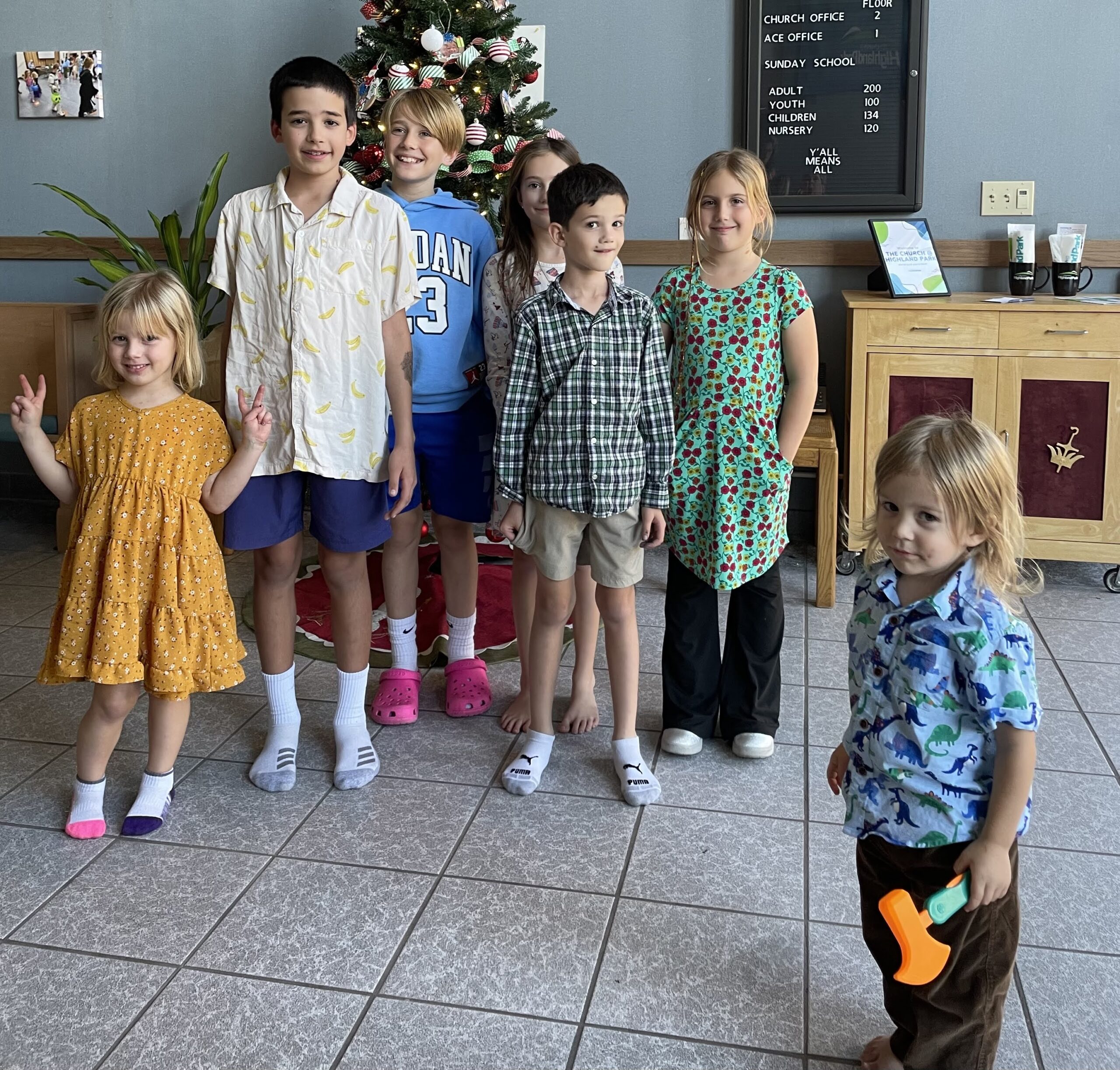 children standing in front of the christmas tree they decorated in the atrium