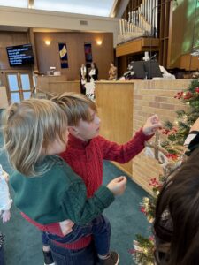 Lochlann and Ambrose Neas put Chrismons on the tree in Highland Park's sanctuary