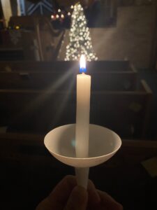 A lit candle at the Christmas Eve service from 2023